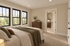 Upstairs bedroom with green bedding and two tall windows, looking toward an adjoining bathroom.