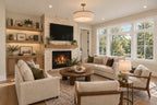 Great room with a stone fireplace, television, wood built-ins and neutral seating beneath wide white-framed windows.