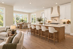 Wood kitchen island with four upholstered stools, white cabinetry and a range hood, with the dining area beside broad windows.