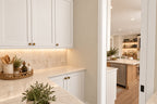 Walk-in pantry with white cabinetry, a pale countertop and tile backsplash, opening to the kitchen island.