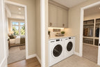 First-floor laundry with a washer and dryer beneath a counter, beside the primary suite walk-in closet and bedroom doorway.