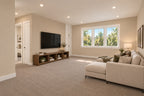 Upstairs loft with a sectional sofa, television console, neutral carpeting and a wide window.