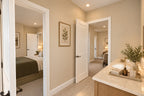 Upstairs shared bathroom with a wood vanity, pale countertop and separate doorways leading to two bedrooms.