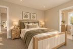 Upstairs bedroom with a wood-framed bed, green throw, matching nightstands and a doorway to the shared bathroom.