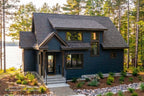 Cottage front exterior rendering with blue siding, a covered entry and upper dormer in a wooded setting.